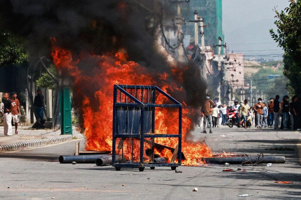 Protesters in Nepal set fire to barricades on a city street in response to social media banΒ